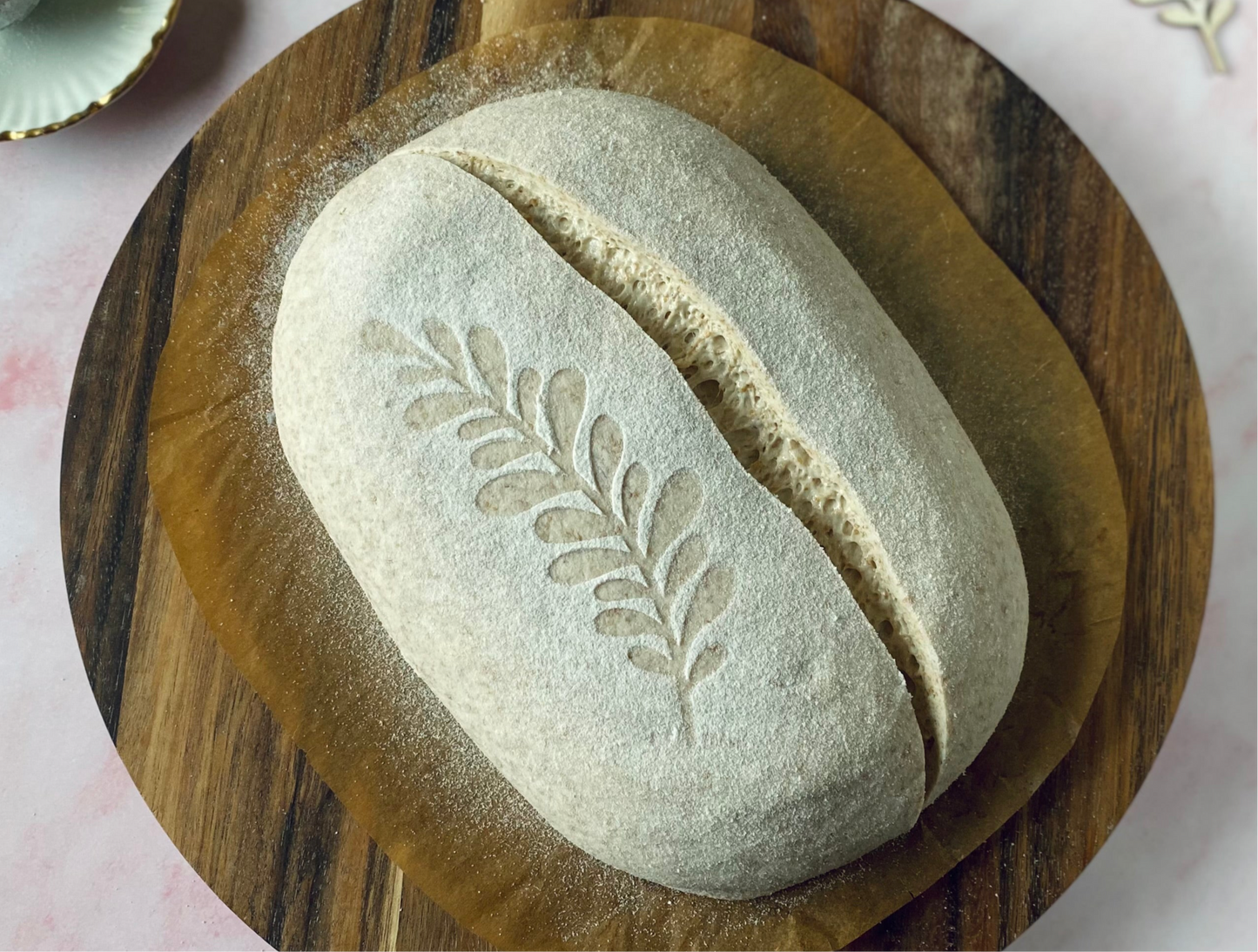 Loaf of bread with leaf design on a wooden board