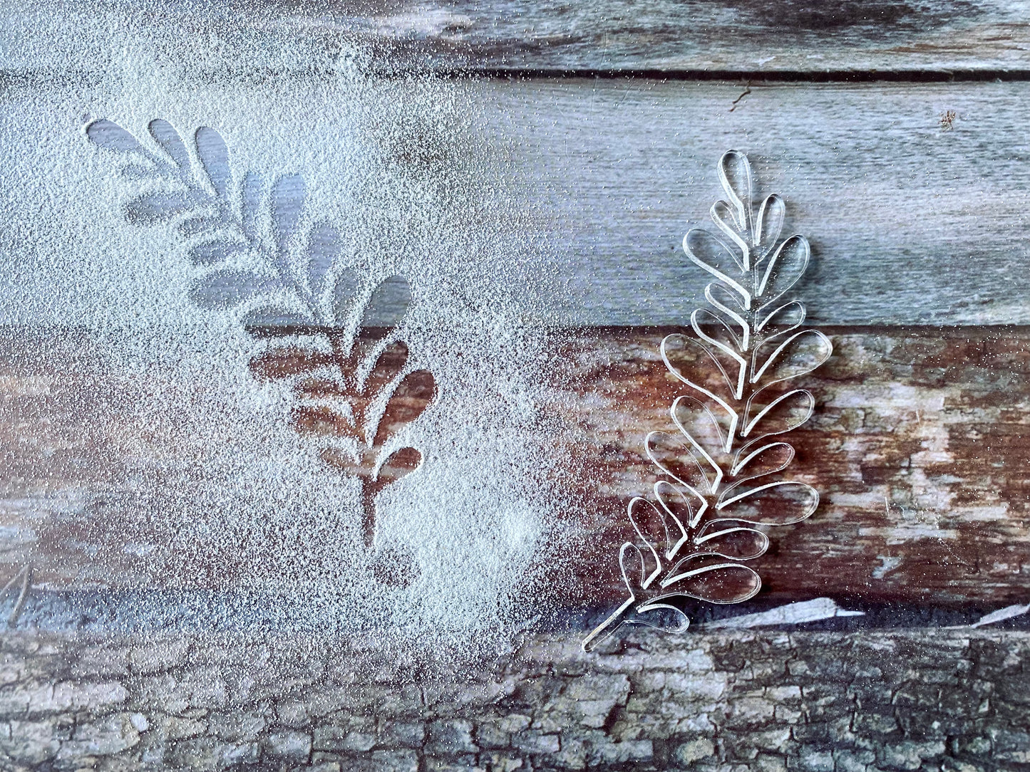 Metal leaf-shaped cookie cutters on a wooden surface with flour.