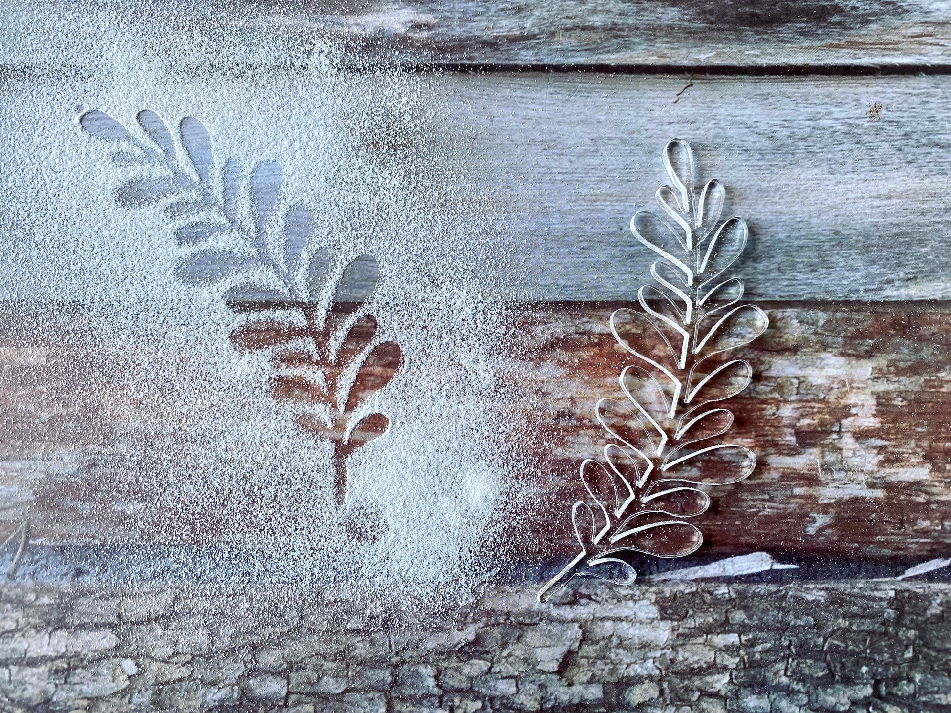 Metal leaf-shaped cookie cutters on a wooden surface with flour.