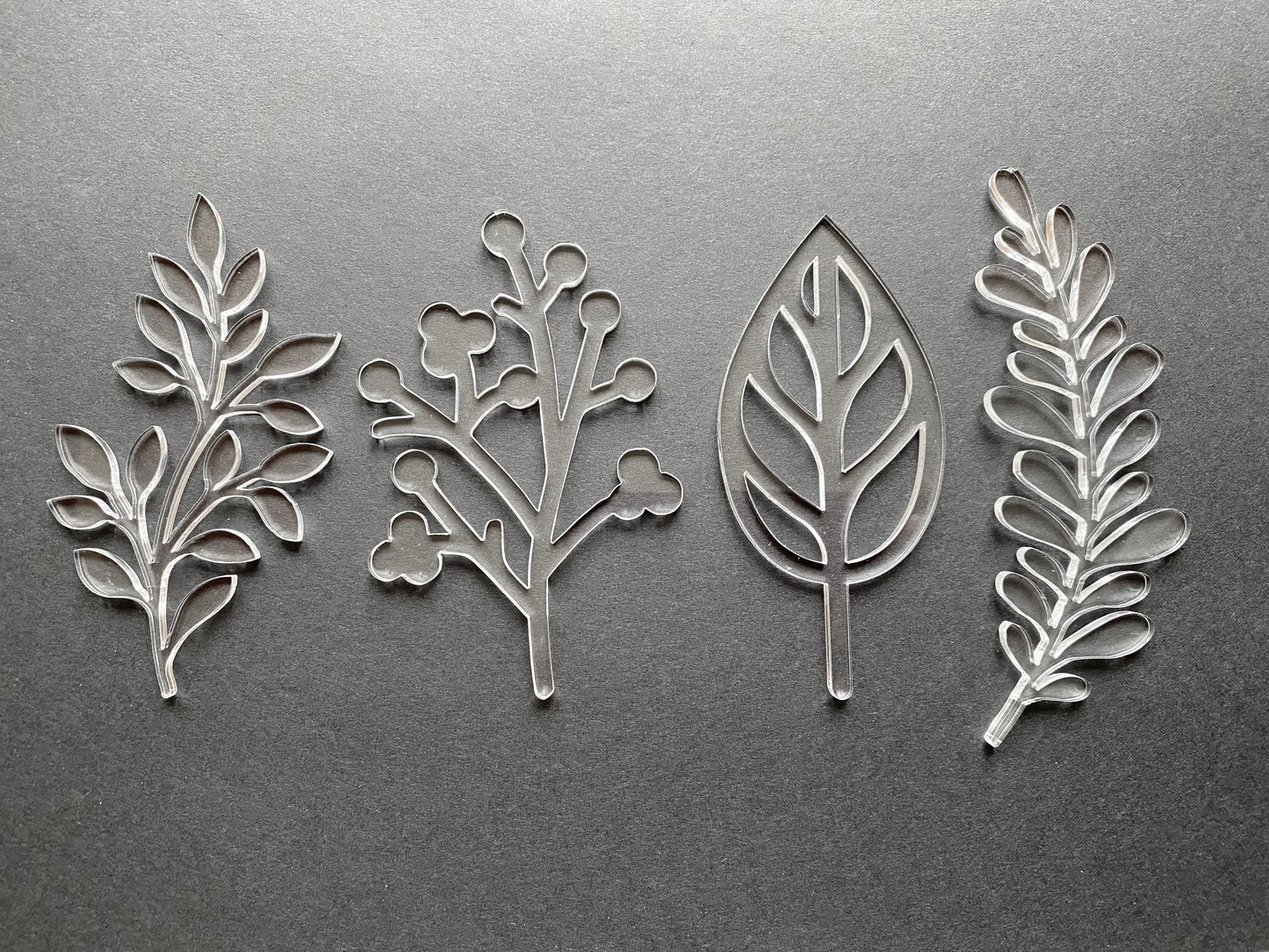Four acrylic leaf-shaped cut outs on a gray background