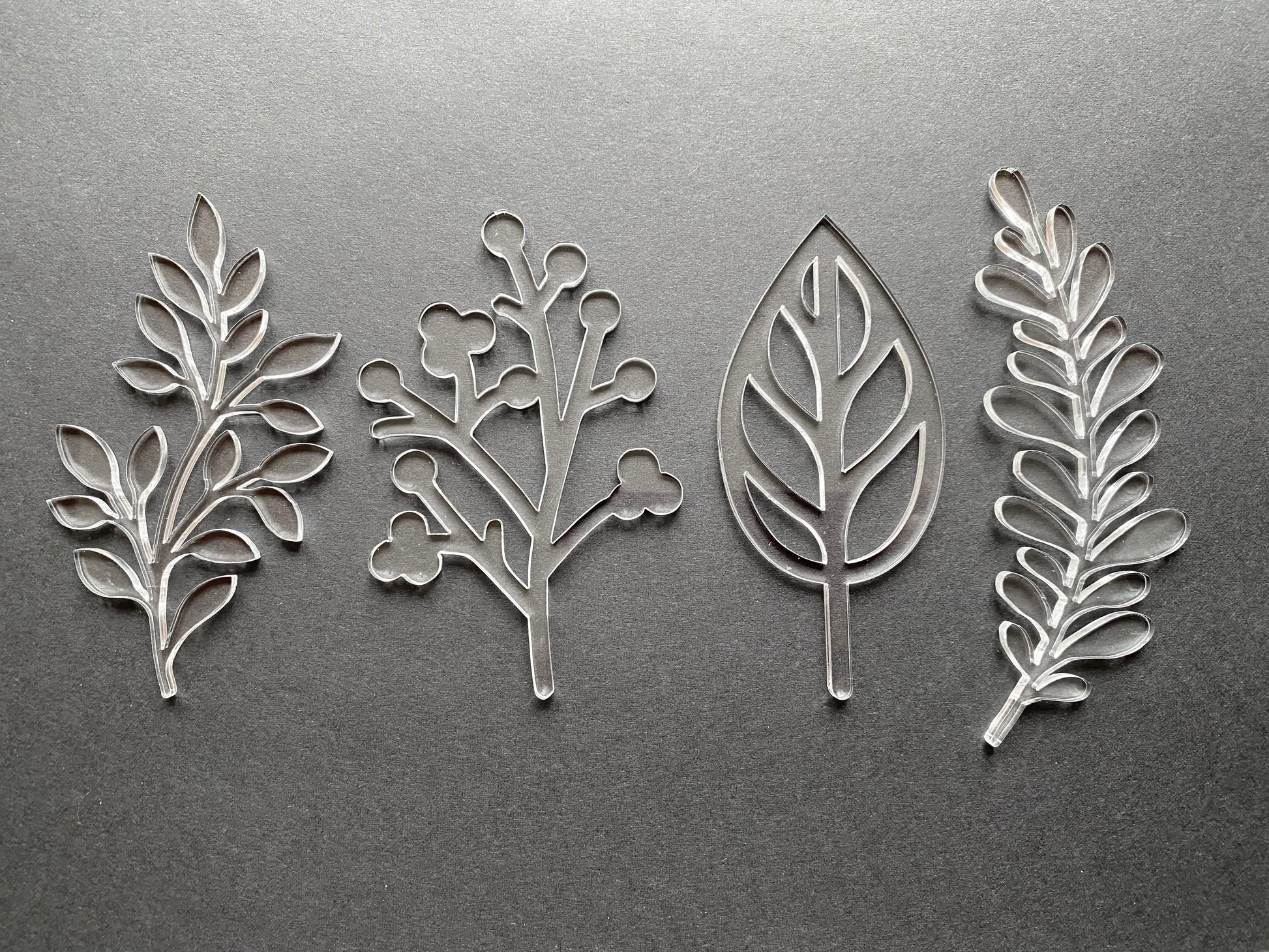 Four acrylic leaf-shaped cut outs on a gray background