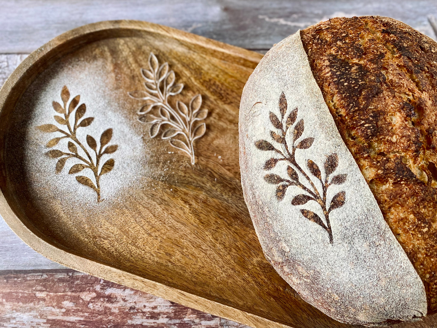 Loaf of bread with leaf pattern on a wooden tray