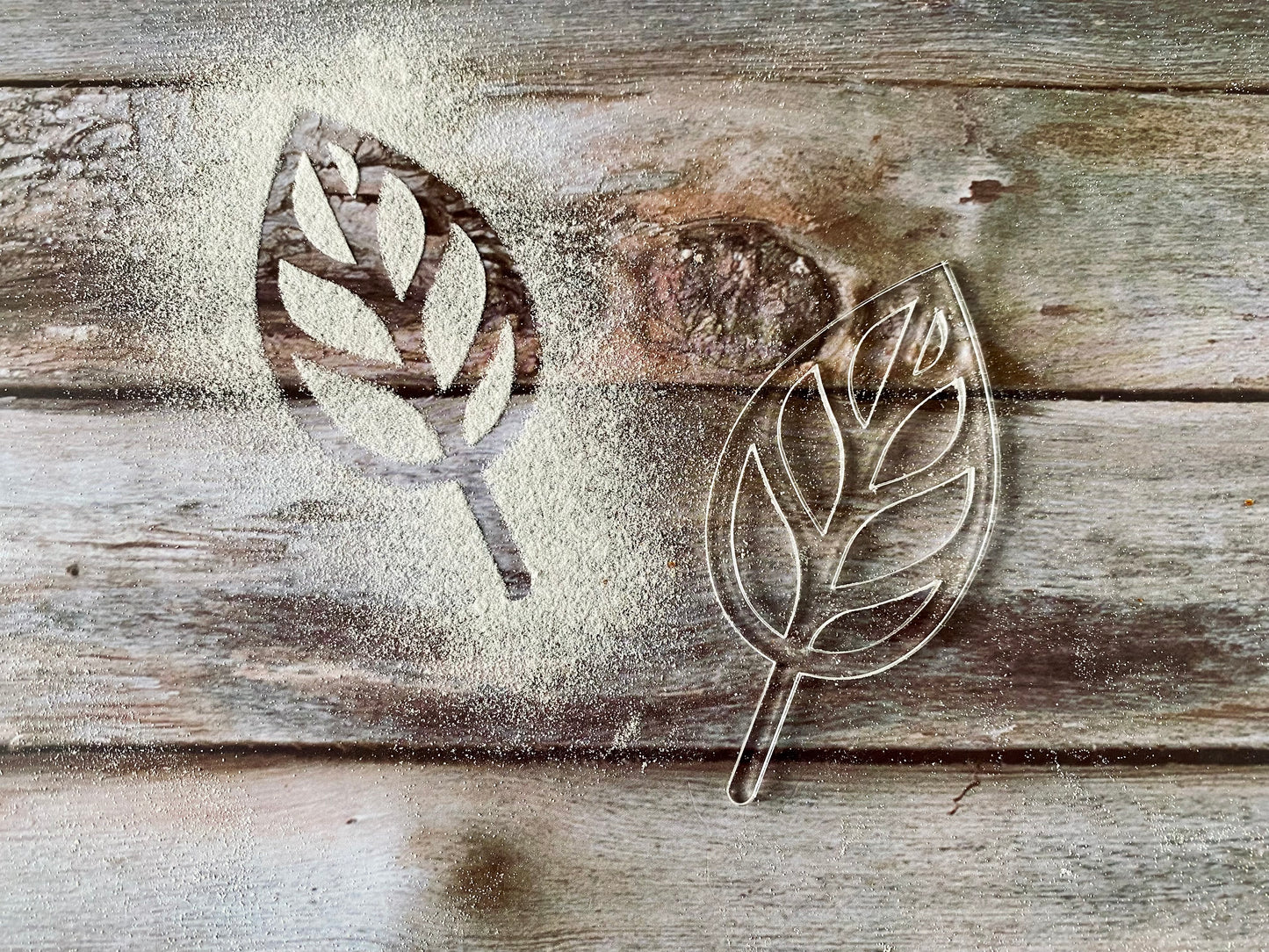 Metal leaf cookie cutters on a wooden surface with flour dust.