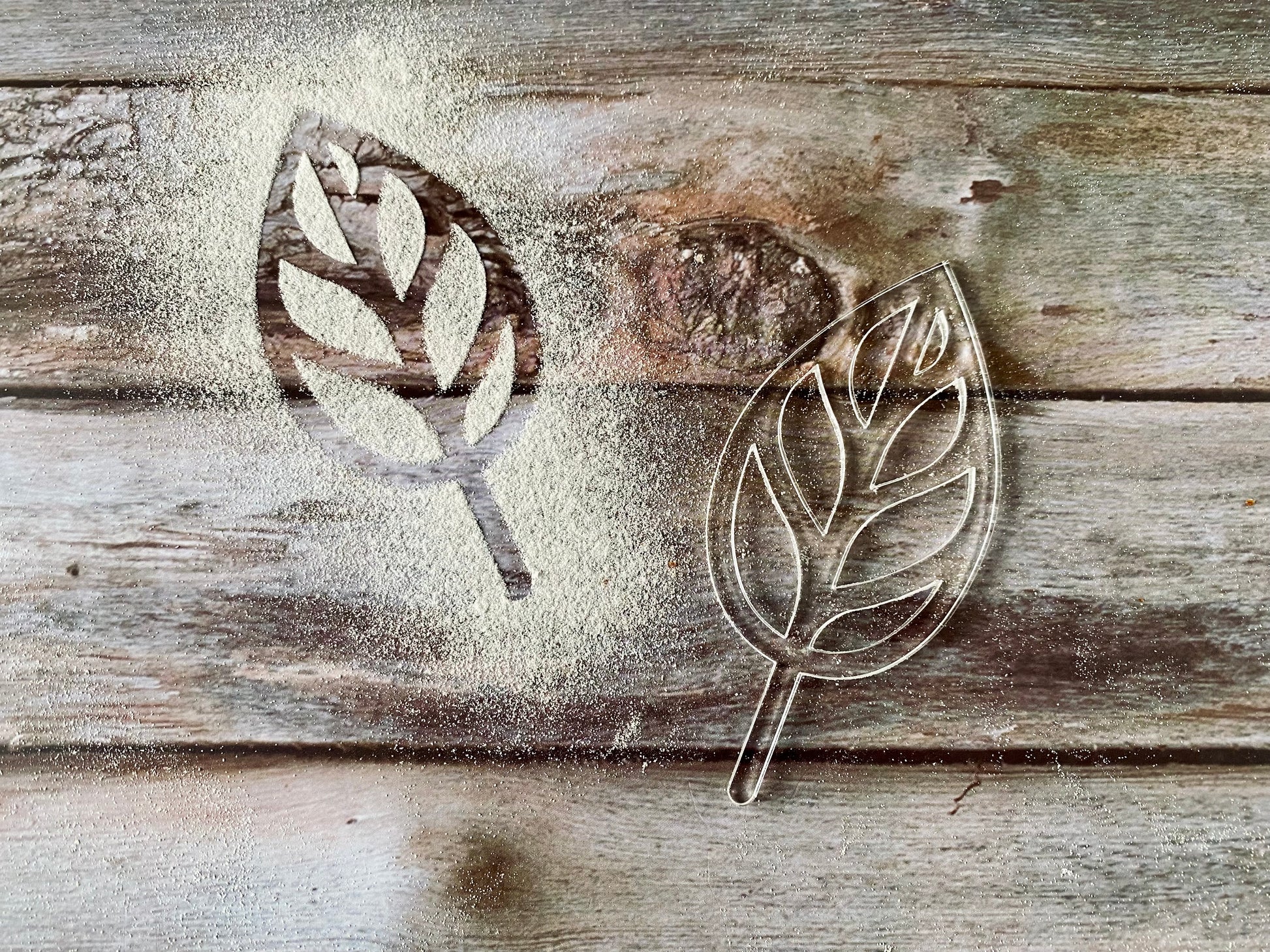 Metal leaf cookie cutters on a wooden surface with flour dust.